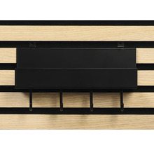 Schwarzes Regal mit Haken an einer Holzpaneelwand