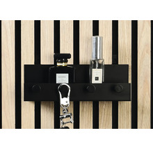 Schlüsselbrett mit Schlüsselanhänger und Parfümflaschen vor einer Holzpaneelwand