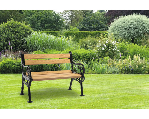 Gartenbank aus Holz und Metall auf Rasen vor üppiger Gartenlandschaft