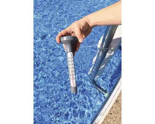 Eine Hand hält ein Poolthermometer im Wasser.