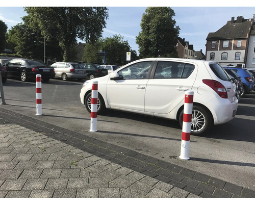 Parkplatz mit rot-weißen Sicherheitspollern und geparkten Autos