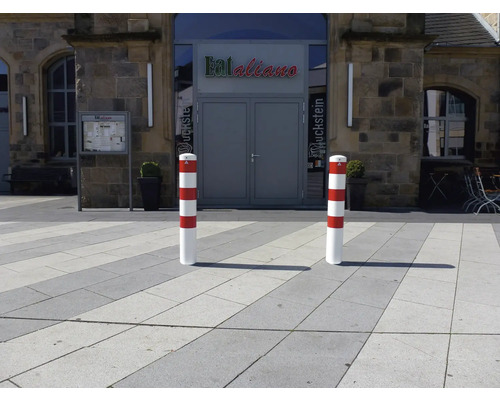 Zwei rot-weiß gestreifte Absperrpfosten vor einem Gebäude.