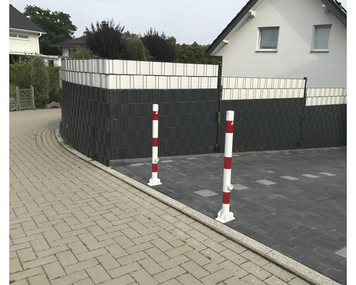 Außenansicht eines Hauses mit Zaun und rot-weißen Sperrpfosten