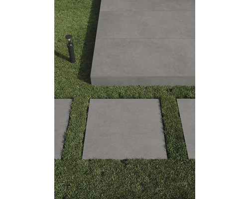 Szene mit grauen Terrassenplatten und Rasenflächen, ergänzt durch eine Außenleuchte.