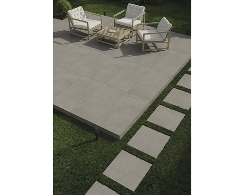 Terrasse mit Outdoor-Sitzgruppe und quadratischen Steinplatten auf Rasen