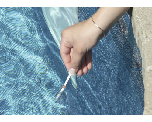 Eine Person testet das Poolwasser mit einem Teststreifen