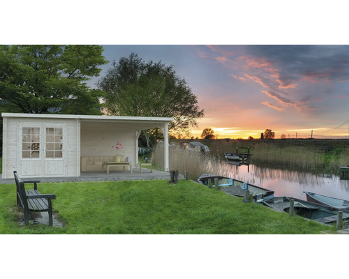 Holzgartenhaus mit Terrasse am Wasser bei Sonnenuntergang.