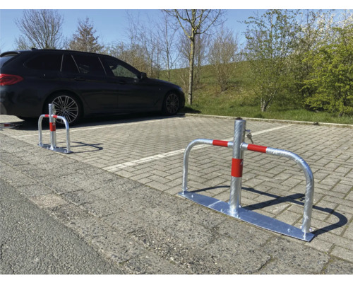 Parkplatzsperre aus Metall mit rotem Band und Auto im Hintergrund