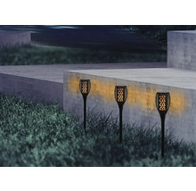 Drei Gartenleuchten mit Flammeneffekt vor einer Betonmauer