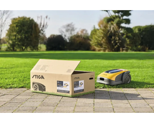 Stiga Logo auf Karton neben Rasenmähroboter auf Rasen