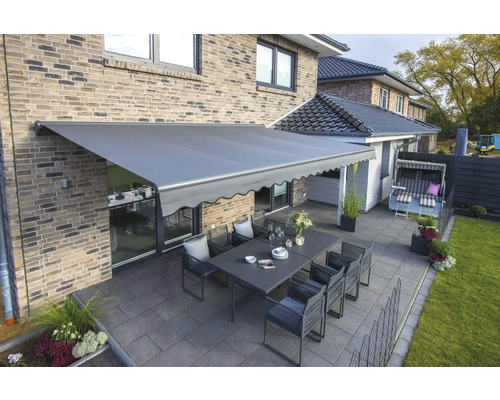 Terrasse mit Markise, Tisch und Stühlen vor einem Haus.