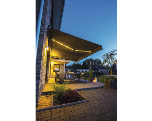 Terrasse mit Markise und Gartenmöbeln am Abend