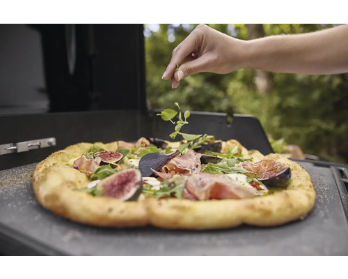 Pizza mit Feigen und Rucola wird mit frischen Kräutern belegt.