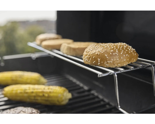 Burgerbrötchen und Maiskolben auf einem Grillrost.