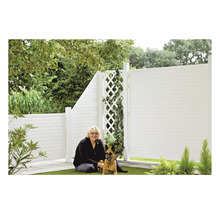 Frau und Hund vor einem weißen Gartenzaun mit Rankgitter.