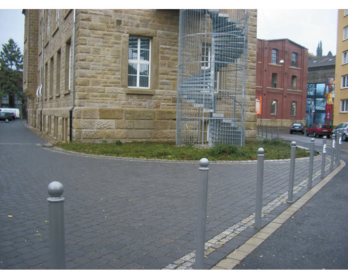 Außenansicht eines Gebäudes mit einer Wendeltreppe und Straßenbegrenzungspfosten.