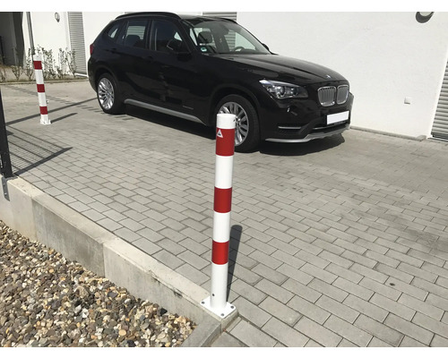 Sperrpfosten rot-weiss vor einem geparkten Auto