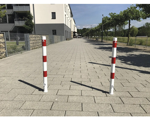 Zwei rot-weiss gestreifte Absperrpfosten auf einem Gehweg.