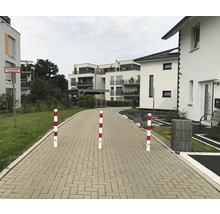 Szene mit mehreren rot-weiß gestreiften Sicherheitspollern auf einem gepflasterten Weg.