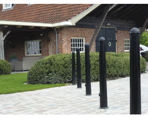 Reihe von schwarzen Pfosten auf einem gepflasterten Weg vor einem Gebäude