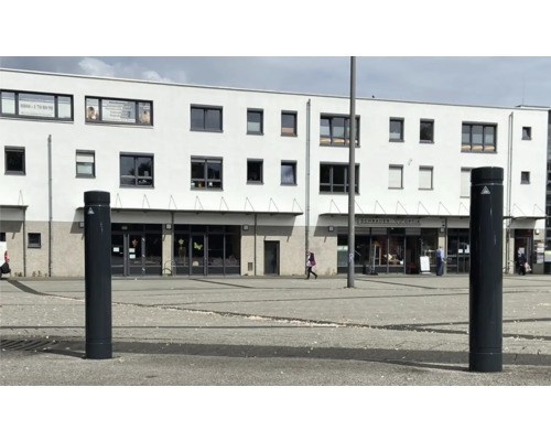 Szene einer Fußgängerzone mit Sicherheitspollern vor einem Gebäude