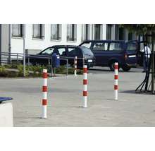 Mehrere rot-weiße Verkehrspfosten auf einem Parkplatz