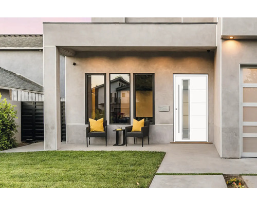 Moderne Hausfassade mit Haustür, Fenstern und Sitzgelegenheit im Freien.