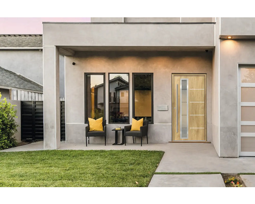 Moderne Hausfassade mit Eingangstür, Fenstern und Sitzgelegenheit auf der Terrasse