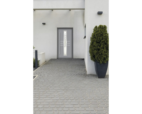 Moderne Haustür mit Glaseinsatz in heller Fassade mit Pflastersteinen.