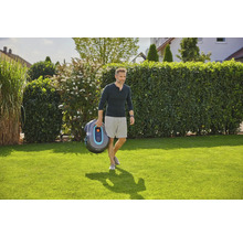 Mann trägt Gardena Mähroboter über Rasen