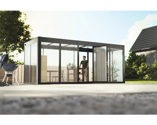 Gewächshaus SunGarden Select 5.2 Polycarbonat 10 mm 548 x 233 cm anthrazit Gartenhaus mit Glasschiebetüren und einer Person im Inneren, umgeben von einem Garten