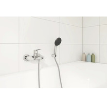 Aufnahme einer Badewanne mit Armatur und Handbrause vor weißem Fliesenhintergrund
