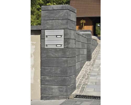 Außenaufnahme eines Briefkastens in einer Mauer aus Betonsteinen