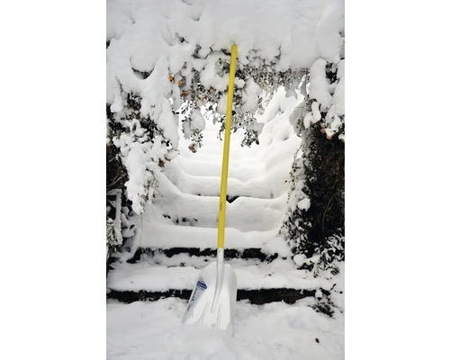 Schneeschaufel mit gelbem Griff vor einer mit Schnee bedeckten Treppe