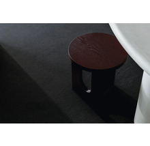 Detailansicht eines schwarzen Teppichs mit einem hölzernen Beistelltisch