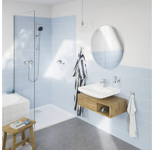 Badezimmer mit Dusche, Waschbecken, Spiegel und hellblauen Fliesen