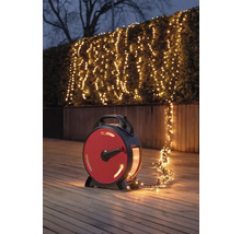 Szene mit einer Lichterkette auf einer Haspel, die einen Strauch im Garten beleuchtet.