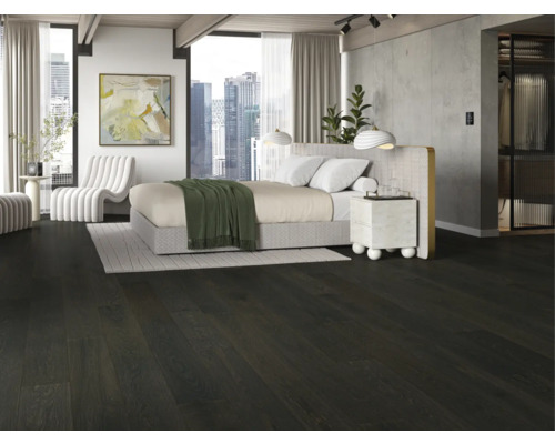 Schlafzimmer mit dunklem Holzboden, Bett und weißem Sessel