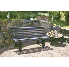 Eine Gartenbank aus Holz und Metall steht im Garten neben einer Feuerstelle.