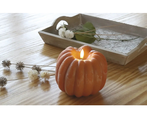 Dekorative Kürbiskerze mit Tablett und floralen Akzenten auf einem Holztisch