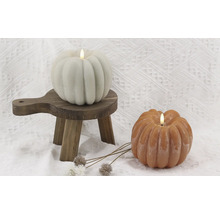 Dekorative Kürbiskerzen auf kleinem Holzschemel