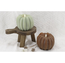 Dekorative Kürbiskerzen auf kleinem Holzschemel und Untergrund