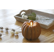 Dekorative Kürbiskerze mit LED-Licht auf einem Tisch mit Holztablett