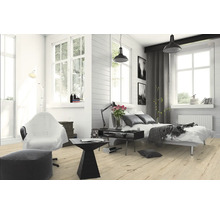 Helles Schlafzimmer mit Bett, Sessel, Stehlampe und Holzboden