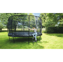 Rundes Gartentrampolin mit Sicherheitsnetz und Leiter im Garten. Ein Kind steigt die Leiter hoch.