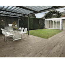 Terrasse mit Terrassenplatten in Holzoptik, Tisch, Stühlen und Grill unter einer Überdachung