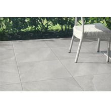 Verlegte graue Terrassenfliesen mit Gartenstuhl