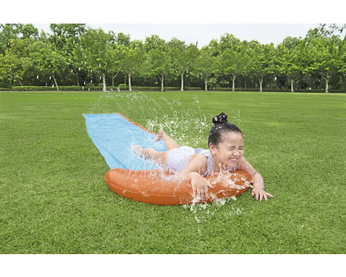 Mädchen hat Spaß auf einer Wasserrutsche im Garten