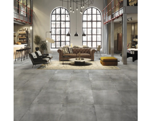 Wohnzimmer mit grauen Bodenfliesen, Ledersofa und hohen Fenstern