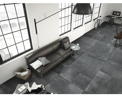 Wohnzimmer mit grauen Bodenfliesen, Sofa, Fenstern und Schreibtisch